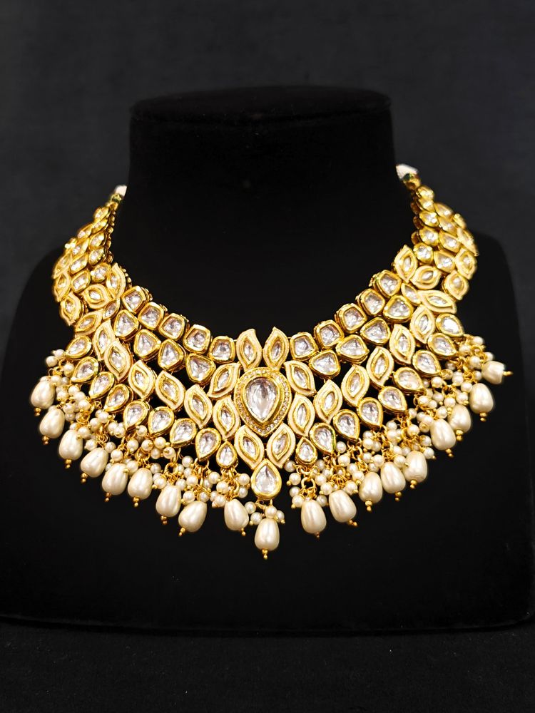 Close-up of an ornate traditional Gold Collar Necklace set, Eaarings and Mangtikka with Kundan, Pearls and American Diamonds. A traditional Kundan artificial necklace set for her wedding ceremony. Royal bridal look featuring a traditional Kundan necklace set.