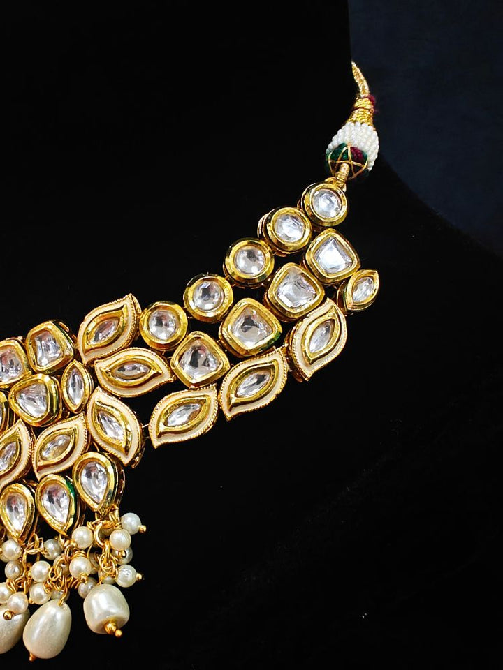 Close-up of an ornate traditional Gold Collar Necklace set, Eaarings and Mangtikka with Kundan, Pearls and American Diamonds. A traditional Kundan artificial necklace set for her wedding ceremony. Royal bridal look featuring a traditional Kundan necklace set.