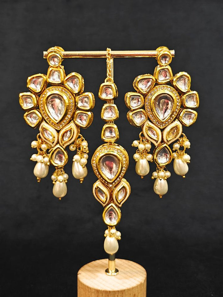 Close-up of an ornate traditional Gold Collar Necklace set, Eaarings and Mangtikka with Kundan, Pearls and American Diamonds. A traditional Kundan artificial necklace set for her wedding ceremony. Royal bridal look featuring a traditional Kundan necklace set.
