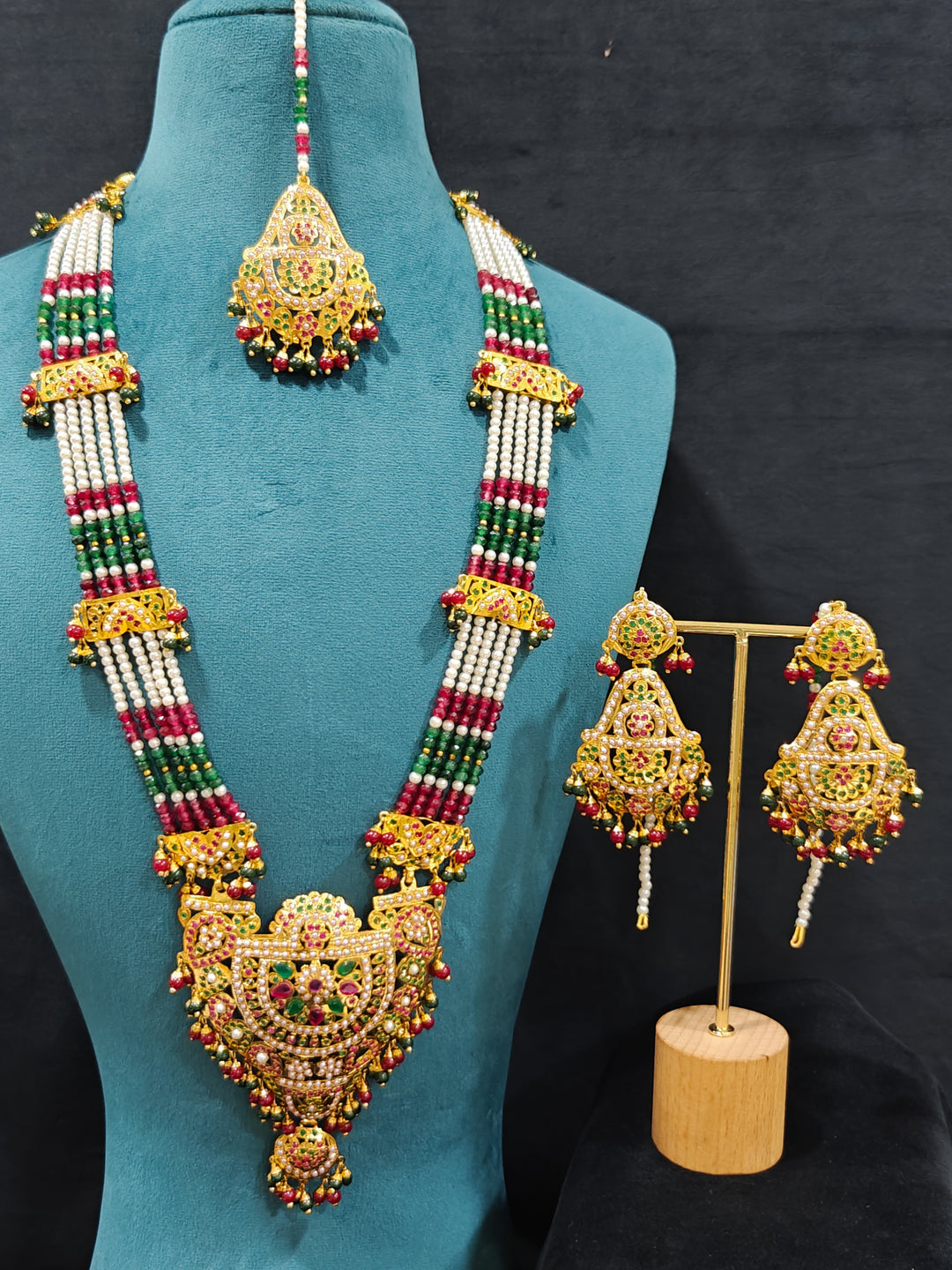 An ornate traditional Long jadau gold jewellery set and  jadau earrings and maangtikka with crystals beads and gemstones. Wedding guest styling a long Jadau artificial necklace. Jadau necklace styled for a wedding guest outfit.

