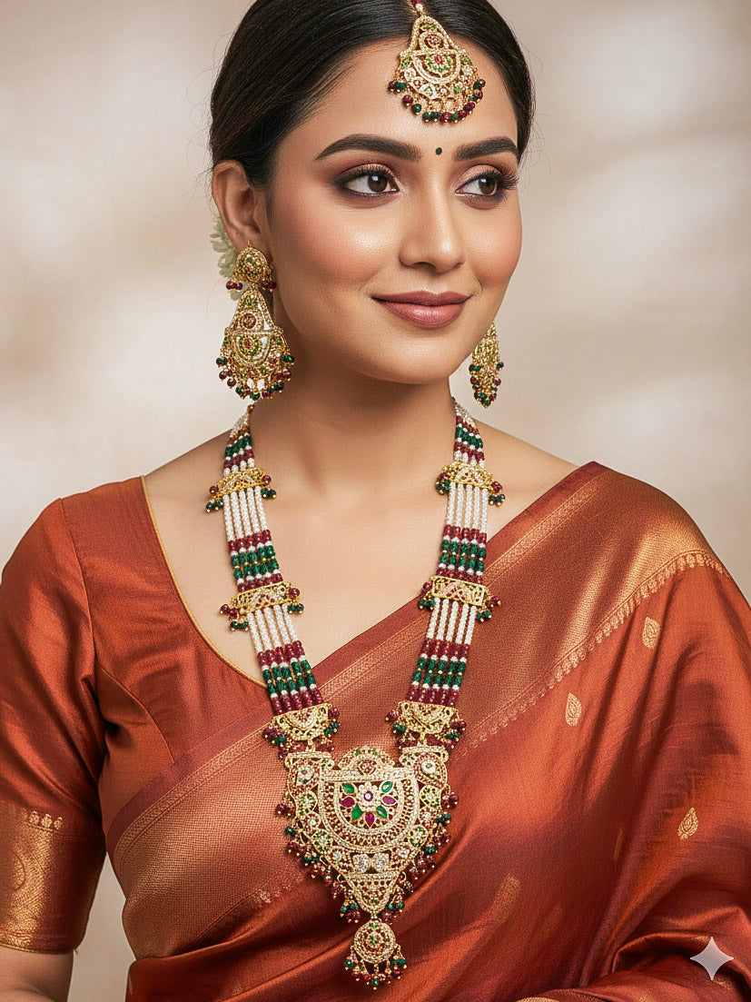 Close-up of a woman wearing an ornate traditional Long jadau gold jewellery set and  jadau earrings and maangtikka with crystals beads and gemstones. Perfect Jadau necklace set for weddings and festivals. 