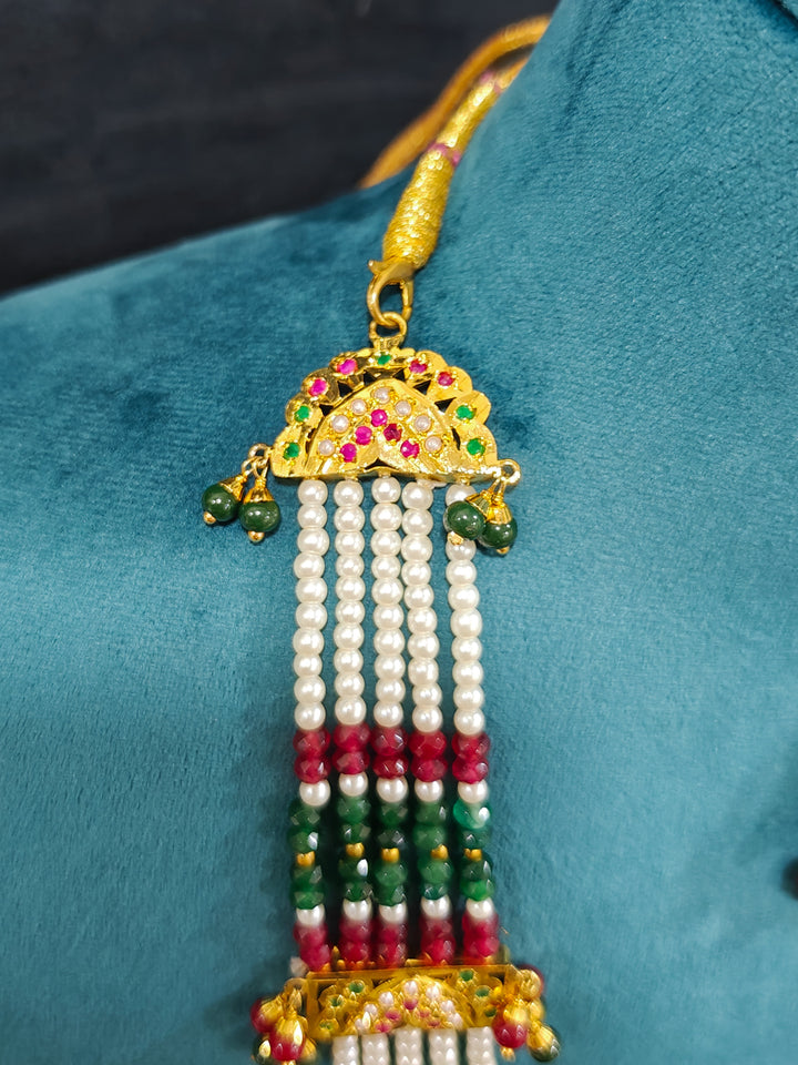 Closeup of an ornate traditional Long jadau gold jewellery set and  jadau earrings and maangtikka with crystals beads and gemstones. Wedding guest styling a long Jadau artificial necklace. Jadau necklace styled for a wedding guest outfit.