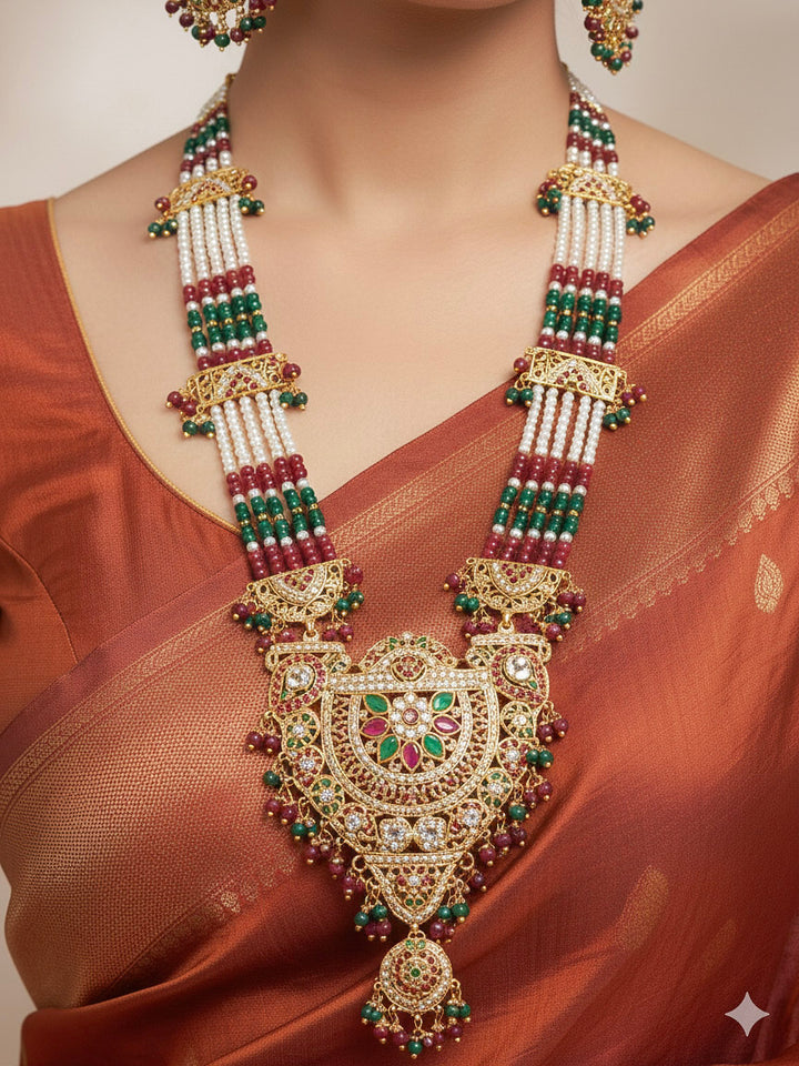 Close-up of a woman wearing a gold Indian traditional jadau jewellery with crystal beads and red and green jadau stones, and matching jadau earringsand maangtika. This authentic jadau jewelry set can we worn as jadau necklace set for weddings. 
