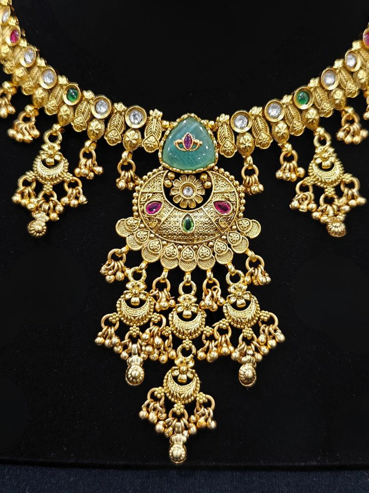 Close-up of a woman wearing an ornate traditional (Gold Polish) Mint Green Collar Haritage jewelry Set & Earrings with Color stones and kundan. Close-up of a royal heritage imitation jewelry set styled with a silk saree. Mehendi ceremony styling featuring a premium heritage artificial jewelry piece.