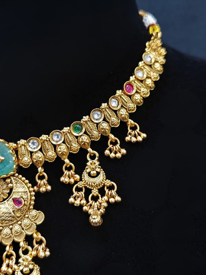 Close-up of a woman wearing an ornate traditional (Gold Polish) Mint Green Collar Haritage jewelry Set & Earrings with Color stones and kundan. Close-up of a royal heritage imitation jewelry set styled with a silk saree. Mehendi ceremony styling featuring a premium heritage artificial jewelry piece.