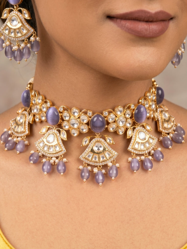 Close-up of a woman wearing an ornate traditional (Gold Polish) Lilac Choker jewellery set and earrings and maangtikka with Polki, Tumble Beads and Lilac Colored Stones. Woman wearing trending Polki artificial jewelry for the wedding season in India. Festive celebration look completed with premium imitation Polki jewelry.