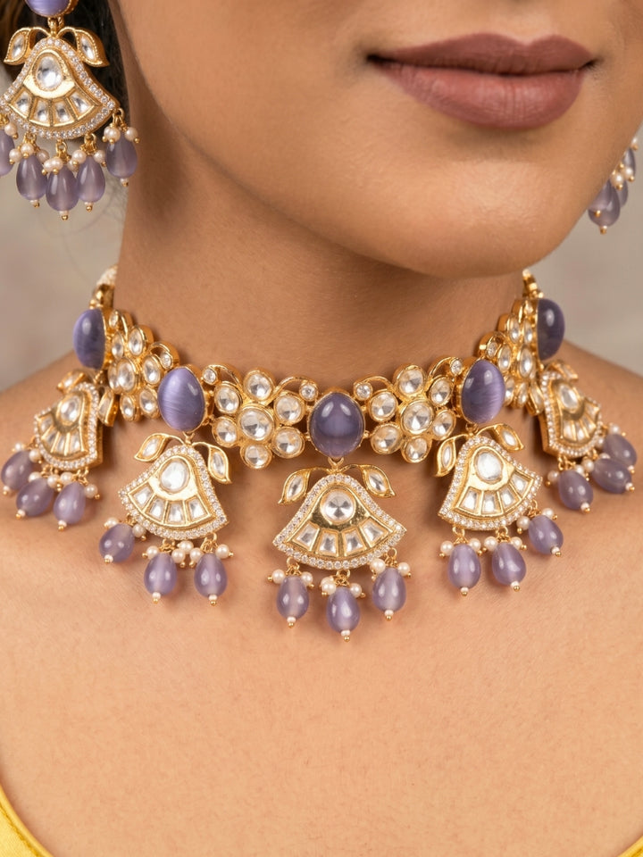 Close-up of a woman wearing an ornate traditional (Gold Polish) Lilac Choker jewellery set and earrings and maangtikka with Polki, Tumble Beads and Lilac Colored Stones. Woman wearing trending Polki artificial jewelry for the wedding season in India. Festive celebration look completed with premium imitation Polki jewelry.