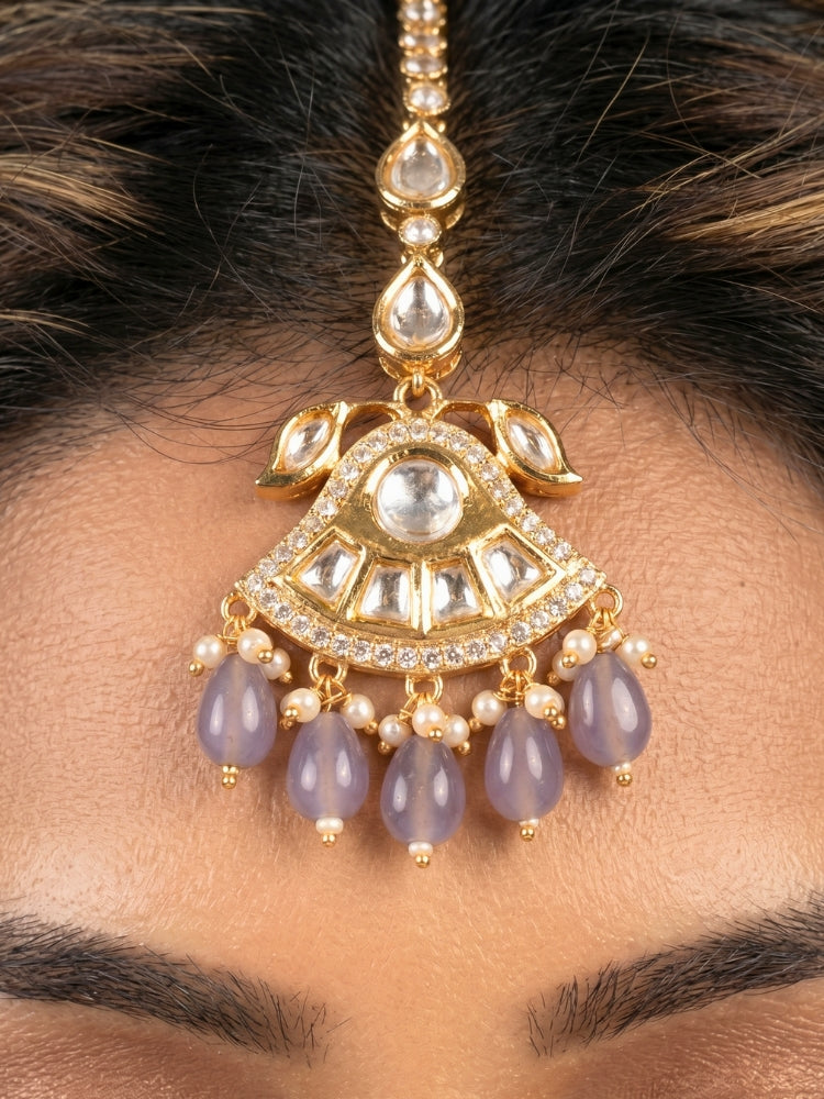 Close-up of a woman wearing an ornate traditional (Gold Polish) Lilac Choker jewellery set and earrings and maangtikka with Polki, Tumble Beads and Lilac Colored Stones. Woman wearing trending Polki artificial jewelry for the wedding season in India. Festive celebration look completed with premium imitation Polki jewelry.