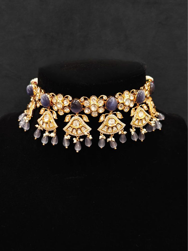 Close-up of an ornate traditional (Gold Polish) Lilac Choker jewellery set and earrings and maangtikka with Polki, Tumble Beads and Lilac Colored Stones. Woman wearing trending Polki artificial jewelry for the wedding season in India. Festive celebration look completed with premium imitation Polki jewelry.