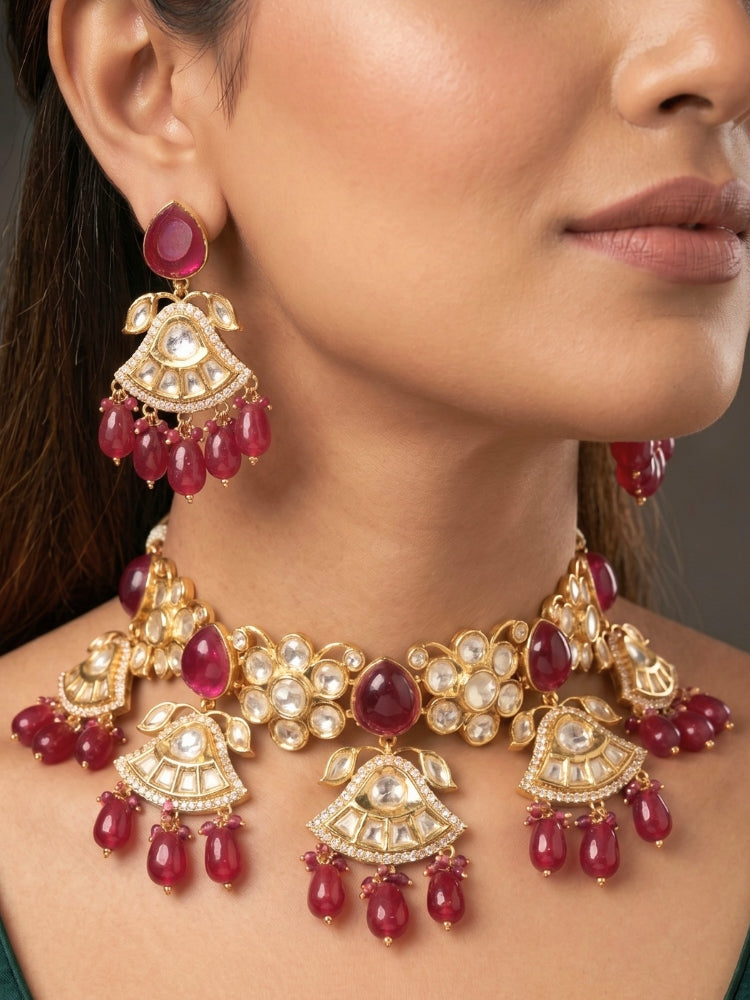 Close-up of a woman wearing an ornate traditional (Gold Polish) Ruby Red Choker jewellery set and earrings and maangtikka with Polki, Tumble Beads and Ruby Red Colored Stones. Woman wearing trending Polki artificial jewelry for the wedding season in India. Festive celebration look completed with premium imitation Polki jewelry.