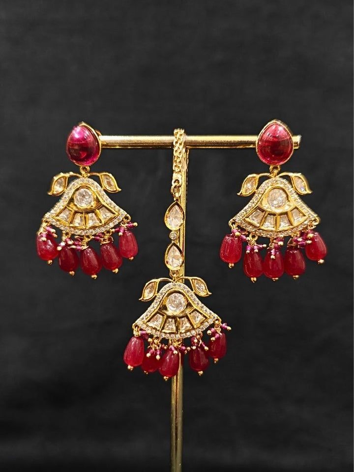 Close-up of an ornate traditional (Gold Polish) Ruby Red Choker jewellery set and earrings and maangtikka with Polki, Tumble Beads and Ruby Red Colored Stones. Woman wearing trending Polki artificial jewelry for the wedding season in India. Festive celebration look completed with premium imitation Polki jewelry.