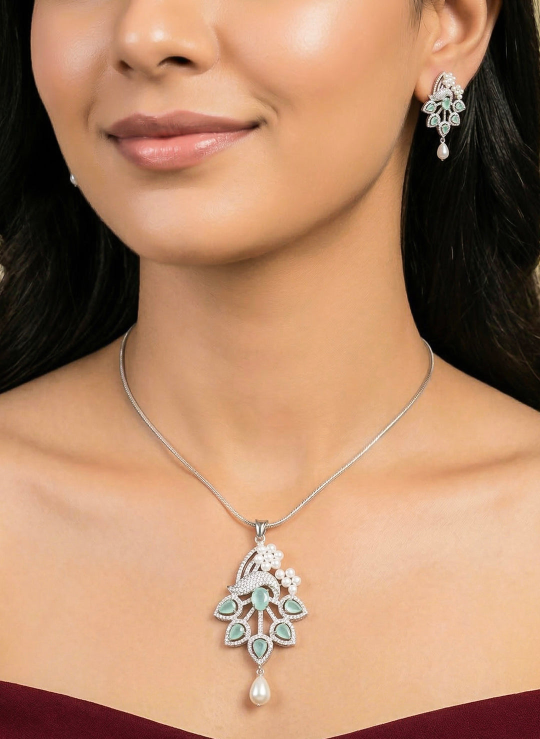 Close-up of a woman wearing an ornate Indo-western Mint Green (Silver Polish)  Pendant set and earrings with American Diamonds, Colored Stones and Pearls. Woman styling a statement American diamond Pendant with an off-shoulder gown for a reception. Indo-western outfit styled with a statement American diamond Pendant set.
