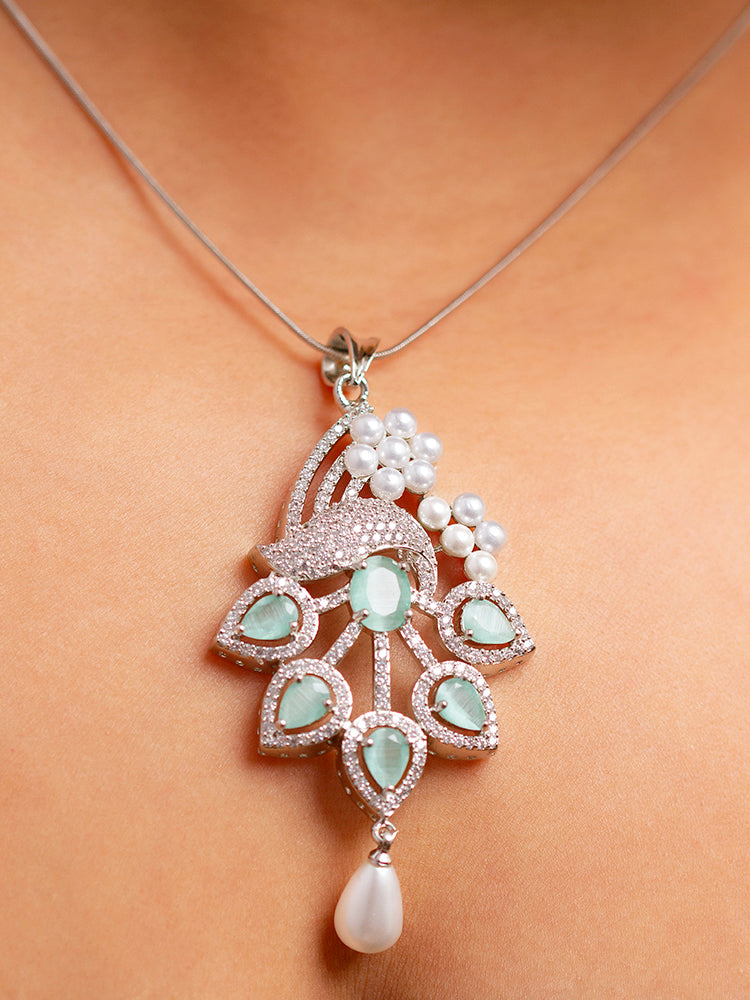 Close-up of a woman wearing an ornate Indo-western Mint Green (Silver Polish)  Pendant set and earrings with American Diamonds, Colored Stones and Pearls. Woman styling a statement American diamond Pendant with an off-shoulder gown for a reception. Indo-western outfit styled with a statement American diamond Pendant set.