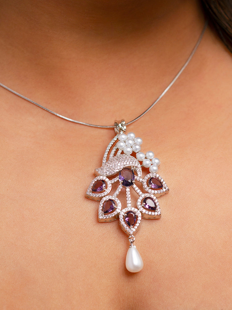 Close-up of a woman wearing an ornate Indo-western Purple (Silver Polish)  Pendant set and earrings with American Diamonds, Colored Stones and Pearls. Woman styling a statement American diamond Pendant with an off-shoulder gown for a reception. Indo-western outfit styled with a statement American diamond Pendant set.