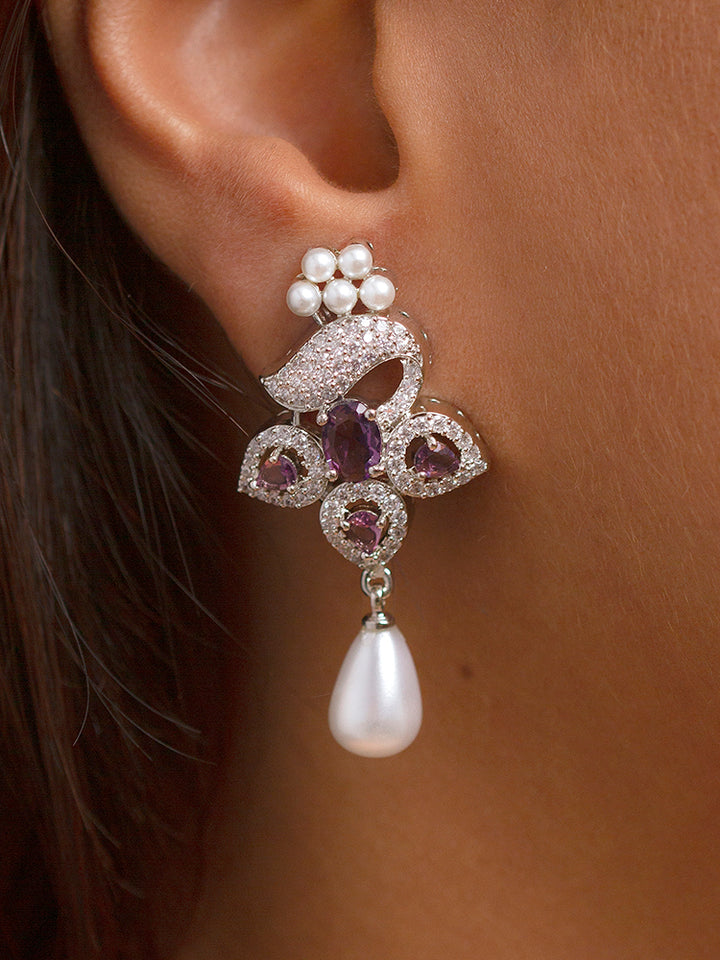 Close-up of a woman wearing an ornate Indo-western Purple (Silver Polish)  Pendant set and earrings with American Diamonds, Colored Stones and Pearls. Woman styling a statement American diamond Pendant with an off-shoulder gown for a reception. Indo-western outfit styled with a statement American diamond Pendant set.