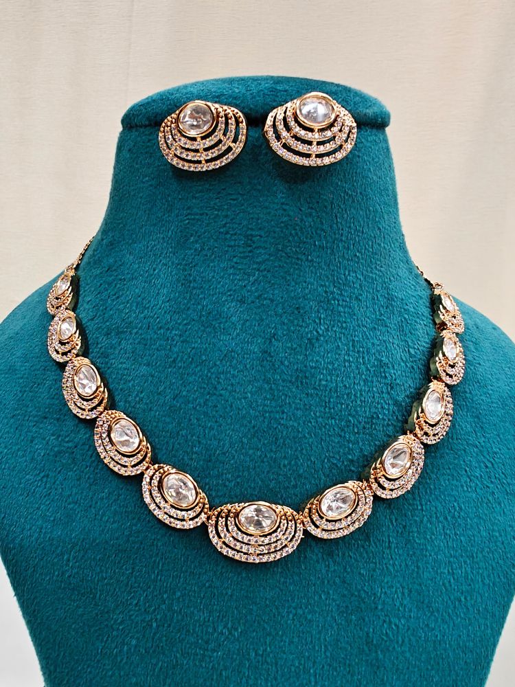 The Alice Necklace Set features a gold moissanite necklace with matching earrings, showcasing oval stones in circular designs made with moissanite, put on a teal velvet bust—perfect for elevating your cocktail jewelry style.
