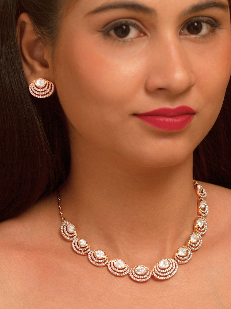 The Alice Necklace Set features a gold moissanite necklace with matching earrings, showcasing oval stones in circular designs made with moissanite, put on a teal velvet bust—perfect for elevating your cocktail jewelry style.