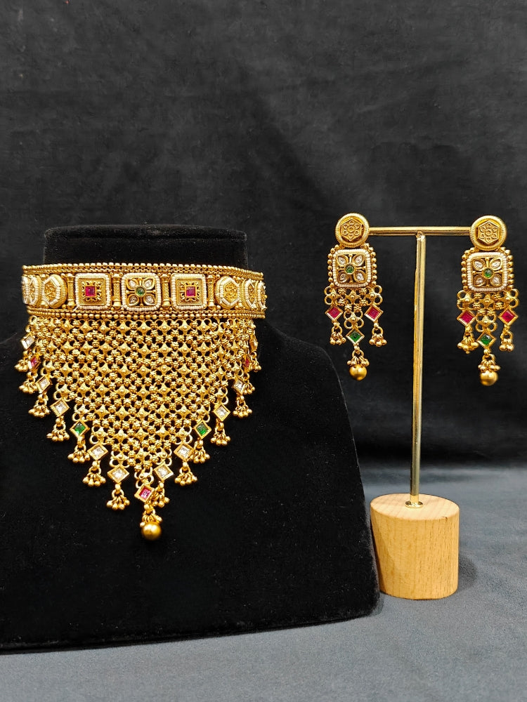 Close-up of an ornate traditional Rajwadi gold Choker jewellery set and earrings with Brass, Stones, Pearls and Bandhai Work. Festive look completed with a luxury Rajwadi imitation necklace. Close-up of a premium Rajwadi artificial necklace under 10000. Perfect Rajwadi necklace set for weddings and festivals.