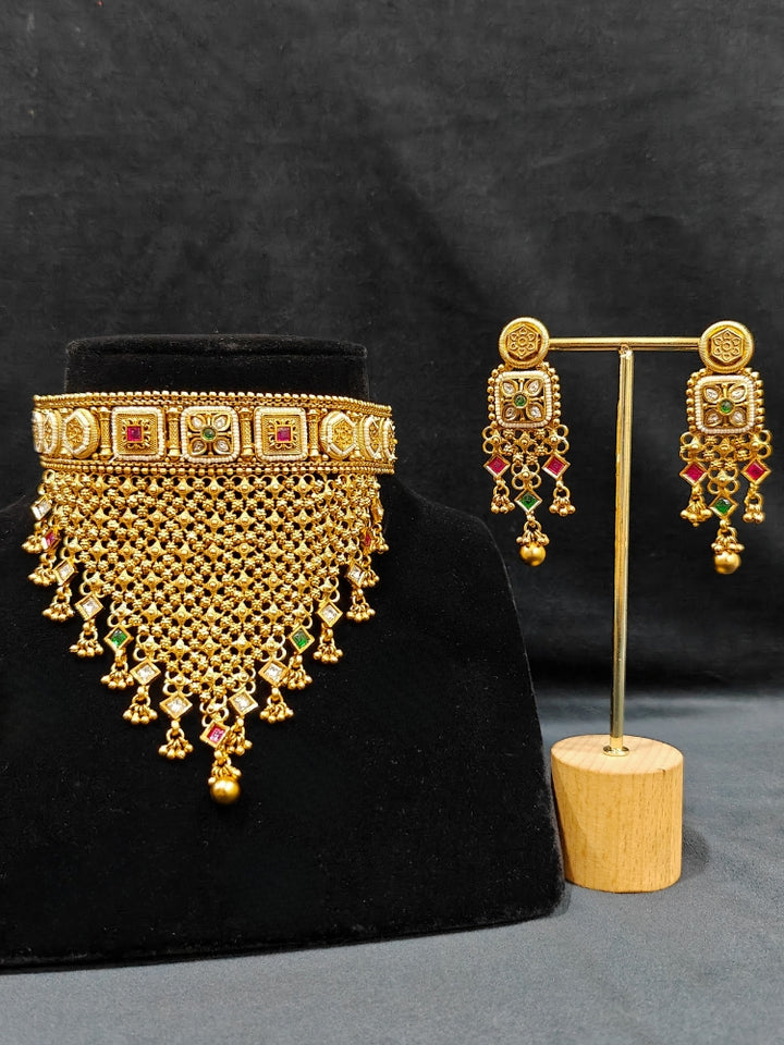 Close-up of an ornate traditional Rajwadi gold Choker jewellery set and earrings with Brass, Stones, Pearls and Bandhai Work. Festive look completed with a luxury Rajwadi imitation necklace. Close-up of a premium Rajwadi artificial necklace under 10000. Perfect Rajwadi necklace set for weddings and festivals.