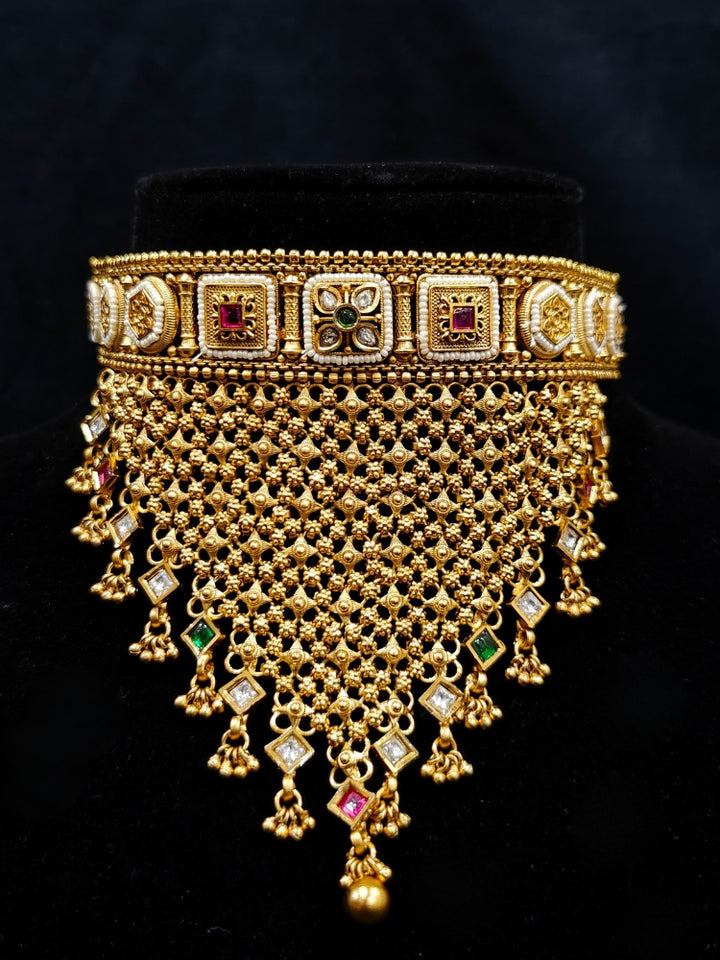 Close-up of an ornate traditional Rajwadi gold Choker jewellery set and earrings with Brass, Stones, Pearls and Bandhai Work. Festive look completed with a luxury Rajwadi imitation necklace. Close-up of a premium Rajwadi artificial necklace under 10000. Perfect Rajwadi necklace set for weddings and festivals.