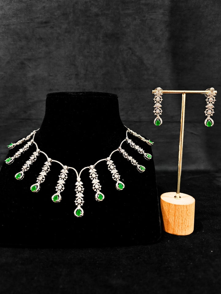 A gorgeous artificial diamond and green colored stone necklace paired with diamond earrings. This artificial diamond jewelry set offers a traditional yet modern touch for Indian brides, designed to add elegance and sophistication to any occasion.