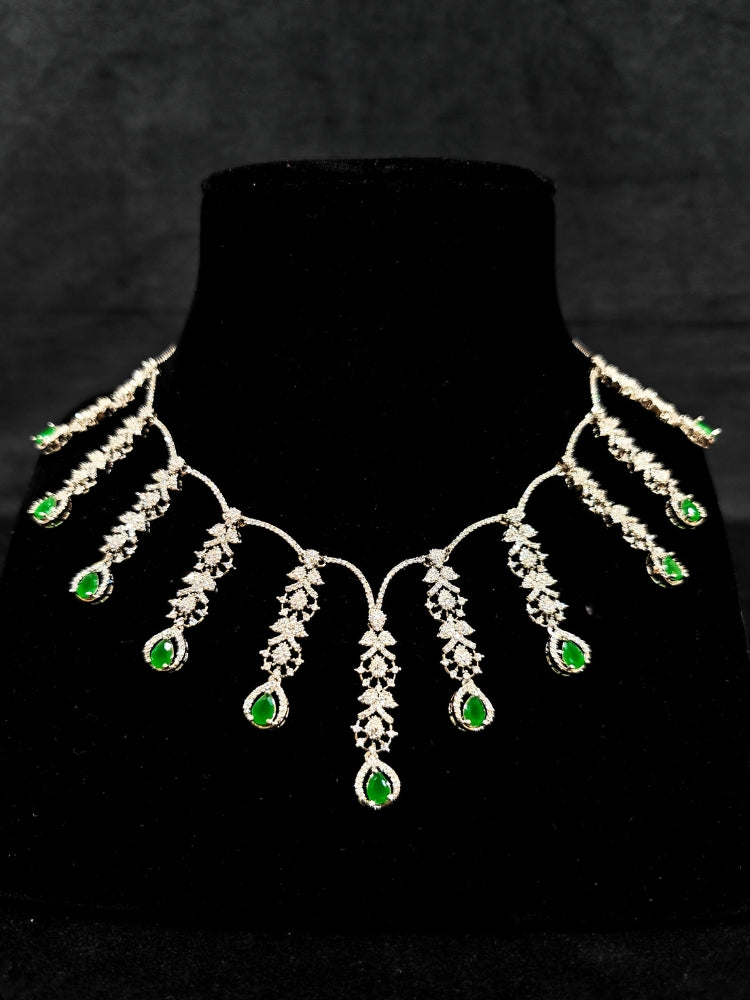  A gorgeous artificial diamond and green colored stone necklace paired with diamond earrings. This artificial diamond jewelry set offers a traditional yet modern touch for Indian brides, designed to add elegance and sophistication to any occasion.