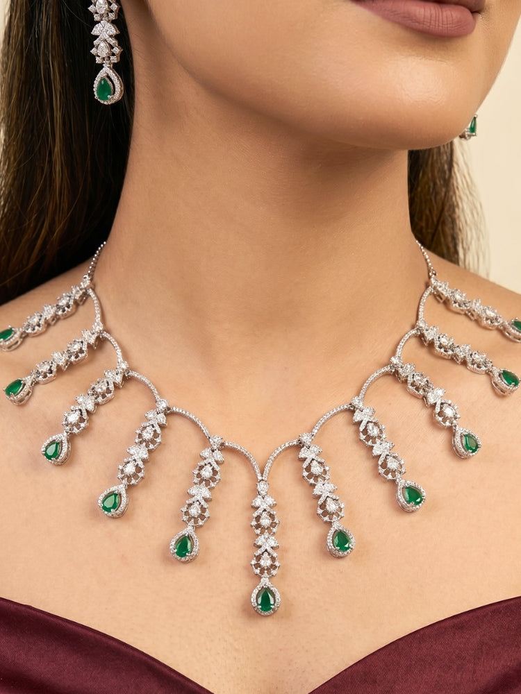 "A woman in a traditional saree, wearing a gorgeous artificial diamond and green colored stone necklace paired with diamond earrings. This artificial diamond jewelry set offers a traditional yet modern touch for Indian brides, designed to add elegance and sophistication to any occasion."
