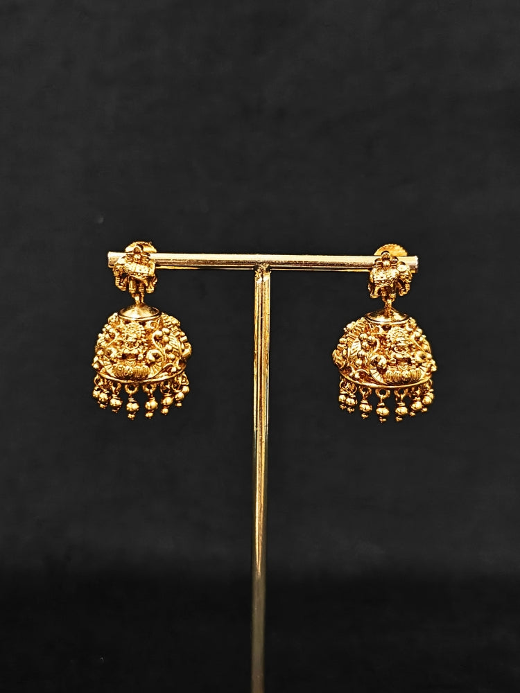 The Ambhira Laxmi Hasli Necklace Set featuring a traditional gold Collar Hasli necklace and matching earrings with Goddess Laxmi in the middle, along with American Diamonds and Colored Stones. Wedding guest look completed with a Hasli temple necklace set.