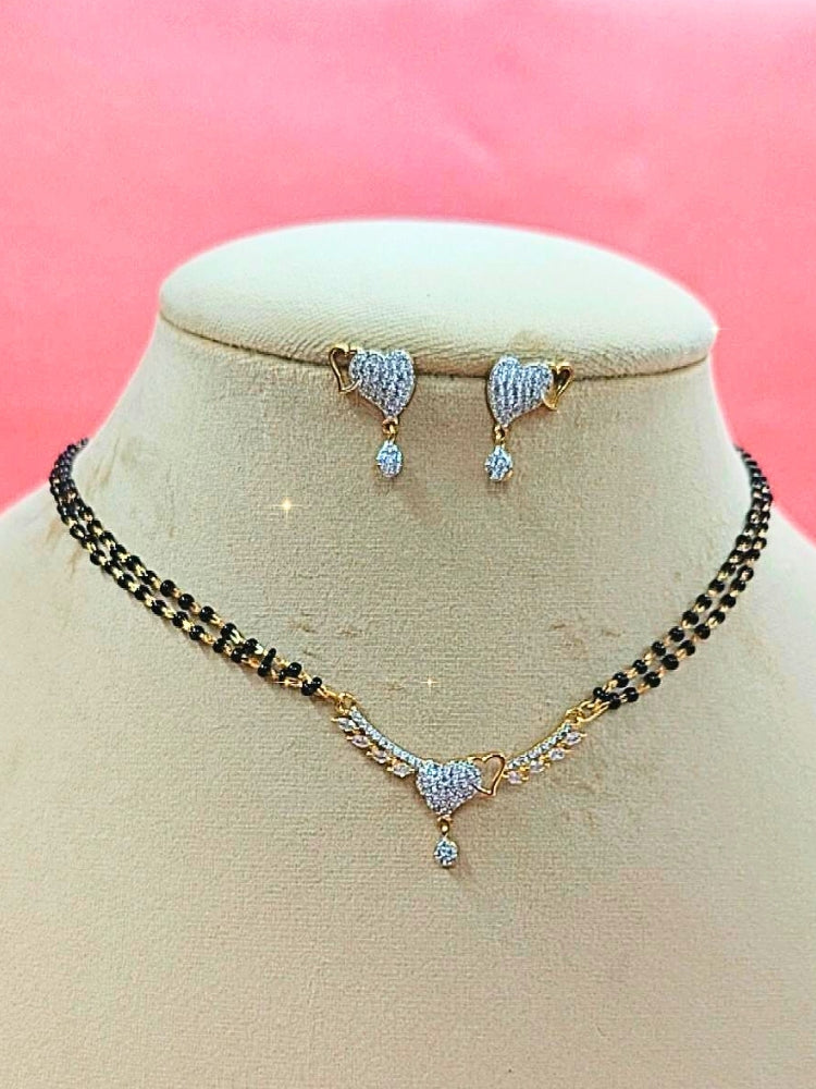 Ambi Mangalsutra—a gold necklace with black mangalsutra beads and matching earrings, pendant featuring sparkling American Diamonds—set against a cream dummy, perfect for your wedding ceremony dress. Diamond mangalsutra. Modern mangalsutra. 