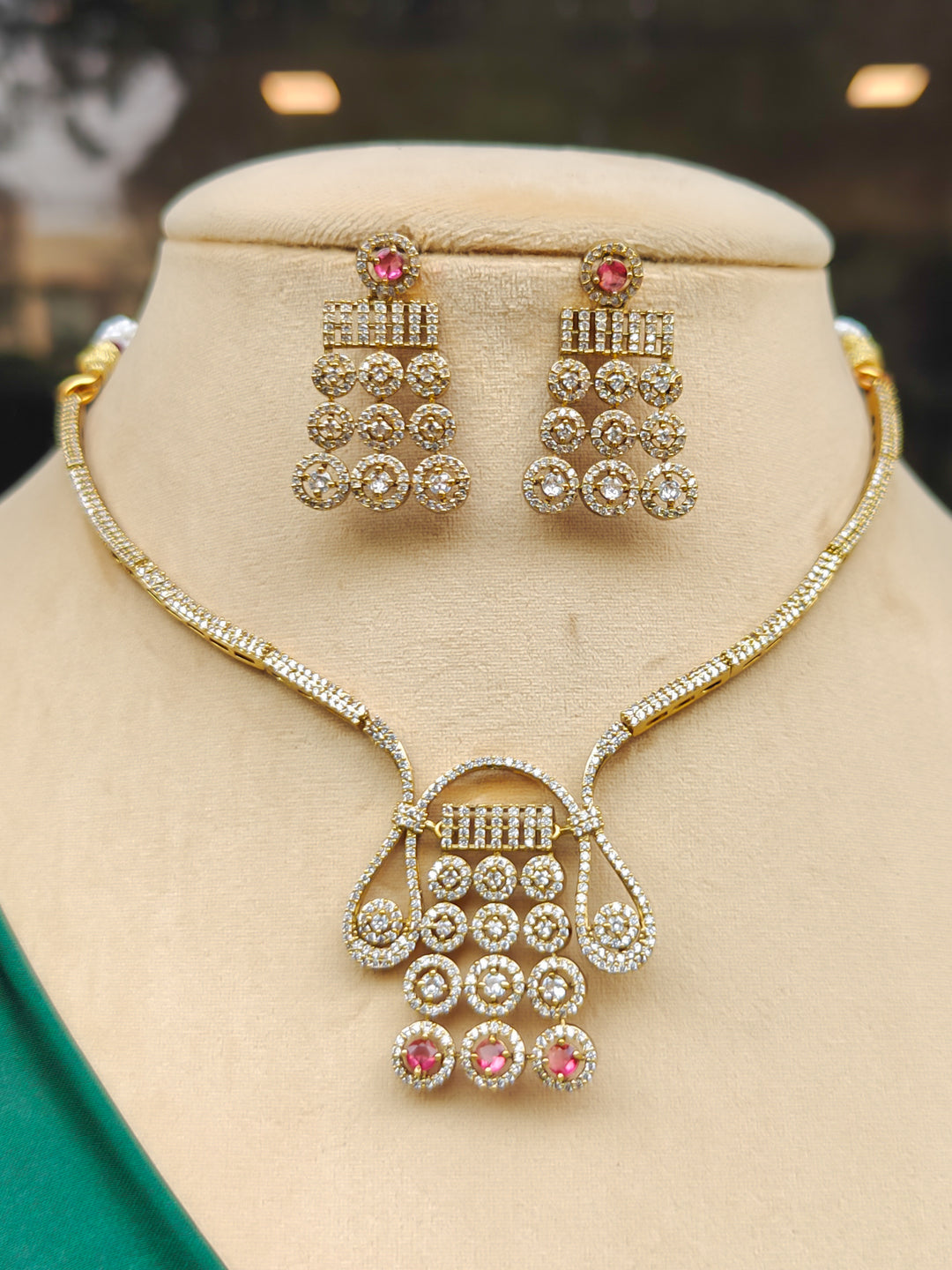 "A beautiful woman wearing an elegant artificial diamond necklace with red colored stone and matching earrings. This premium artificial diamond jewelry set is perfect for special occasions, from Indian weddings to engagement parties, offering sophisticated glamour without the high price tag."
