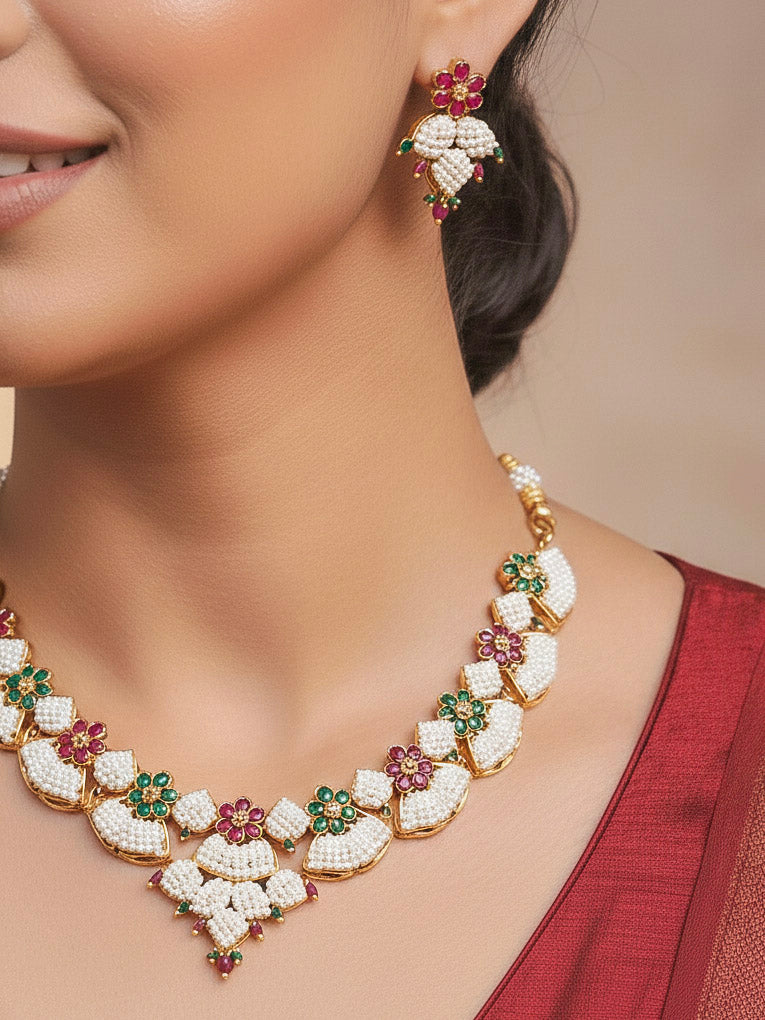 Close-up of a women wearing an ornate traditional (Bright Gold Polish) Red, Green and White Collar jewellery set and earrings and Ring with Pearls and Red & Green Colored Stones. Mehendi ceremony look completed with a handcrafted Pearl jewelry set. Woman wearing a vibrant Pearl artificial jewelry set for celebrations.
