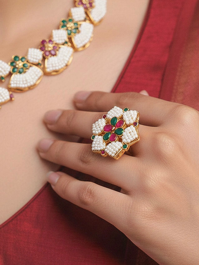 Close-up of a women wearing an ornate traditional (Bright Gold Polish) Red, Green and White Collar jewellery set and earrings and Ring with Pearls and Red & Green Colored Stones. Mehendi ceremony look completed with a handcrafted Pearl jewelry set. Woman wearing a vibrant Pearl artificial jewelry set for celebrations.