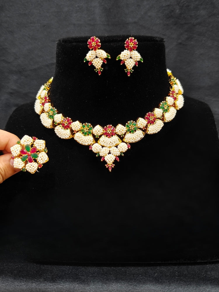 Close-up of an ornate traditional (Bright Gold Polish) Red, Green and White Collar jewellery set and earrings and Ring with Pearls and Red & Green Colored Stones. Mehendi ceremony look completed with a handcrafted Pearl jewelry set. Woman wearing a vibrant Pearl artificial jewelry set for celebrations.