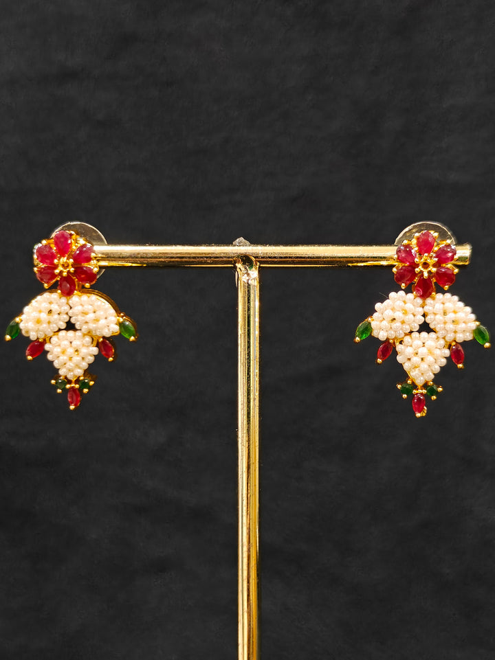 Close-up of an ornate traditional (Bright Gold Polish) Red, Green and White Collar jewellery set and earrings and Ring with Pearls and Red & Green Colored Stones. Mehendi ceremony look completed with a handcrafted Pearl jewelry set. Woman wearing a vibrant Pearl artificial jewelry set for celebrations.