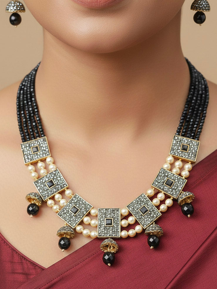 Close-up of a woman wearing an ornate traditional Black Collar jewellery set and earrings with Black Crystals Beads, Pearls, Chatten Squares and Colored Stones. Mehendi ceremony look completed with a handcrafted Pearl jewelry set. Bride showcasing a traditional Pearl artificial jewelry set in India.
