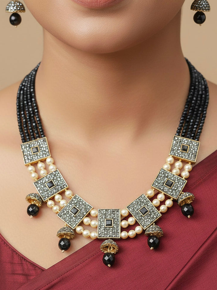 Close-up of a woman wearing an ornate traditional Black Collar jewellery set and earrings with Black Crystals Beads, Pearls, Chatten Squares and Colored Stones. Mehendi ceremony look completed with a handcrafted Pearl jewelry set. Bride showcasing a traditional Pearl artificial jewelry set in India.