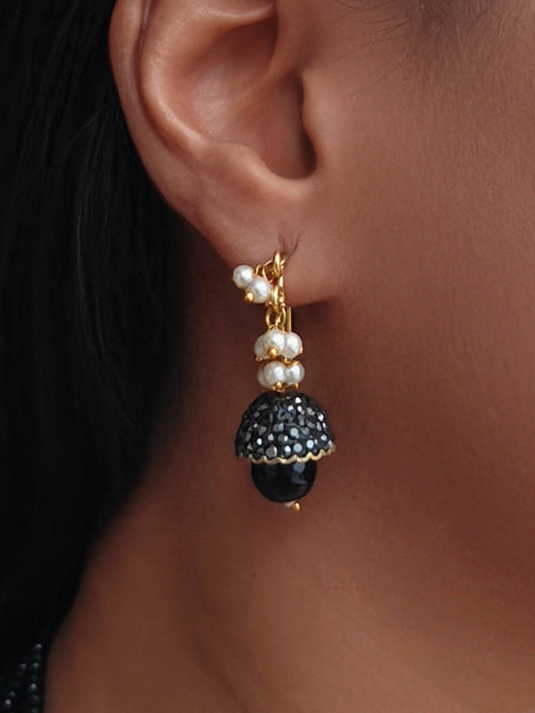 Close-up of a woman wearing an ornate traditional Black Collar jewellery set and earrings with Black Crystals Beads, Pearls, Chatten Squares and Colored Stones. Mehendi ceremony look completed with a handcrafted Pearl jewelry set. Bride showcasing a traditional Pearl artificial jewelry set in India.