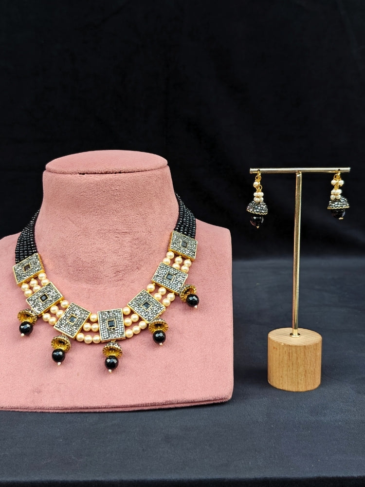 Close-up of an ornate traditional Black Collar jewellery set and earrings with Black Crystals Beads, Pearls, Chatten Squares and Colored Stones. Mehendi ceremony look completed with a handcrafted Pearl jewelry set. Bride showcasing a traditional Pearl artificial jewelry set in India.