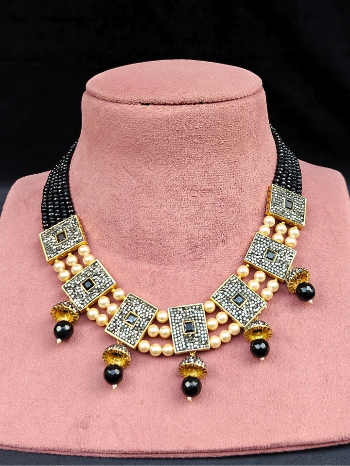 Close-up of an ornate traditional Black Collar jewellery set and earrings with Black Crystals Beads, Pearls, Chatten Squares and Colored Stones. Mehendi ceremony look completed with a handcrafted Pearl jewelry set. Bride showcasing a traditional Pearl artificial jewelry set in India.