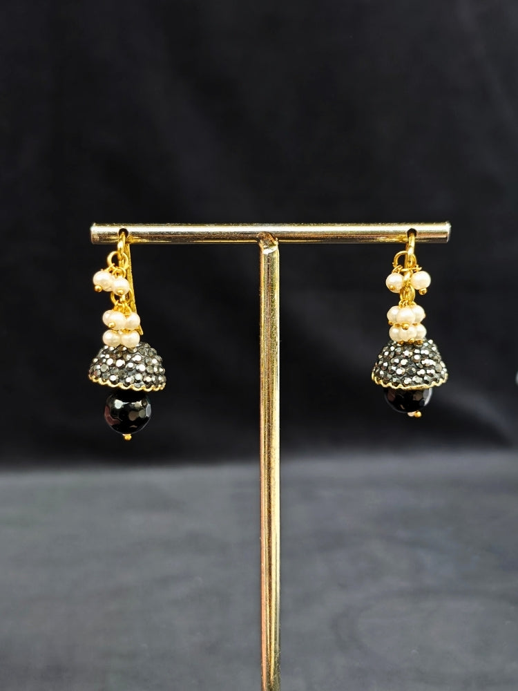 Close-up of an ornate traditional Black Collar jewellery set and earrings with Black Crystals Beads, Pearls, Chatten Squares and Colored Stones. Mehendi ceremony look completed with a handcrafted Pearl jewelry set. Bride showcasing a traditional Pearl artificial jewelry set in India.