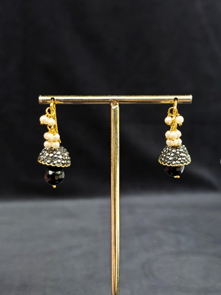 Close-up of an ornate traditional Black Collar jewellery set and earrings with Black Crystals Beads, Pearls, Chatten Squares and Colored Stones. Mehendi ceremony look completed with a handcrafted Pearl jewelry set. Bride showcasing a traditional Pearl artificial jewelry set in India.