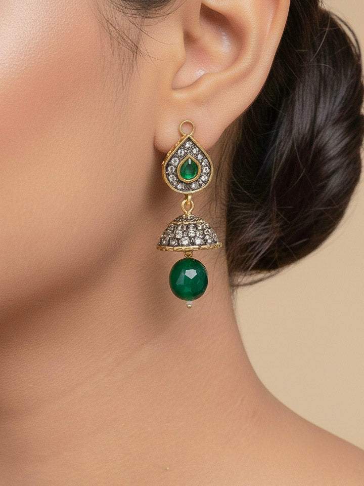 Close-up of a woman wearing an ornate traditional Dark Green Collar jewellery set and earrings with Dark Green Crystals Beads, Pearls, Chatten Squares and Colored Stones. Mehendi ceremony look completed with a handcrafted Pearl jewelry set. Bride showcasing a traditional Pearl artificial jewelry set in India.