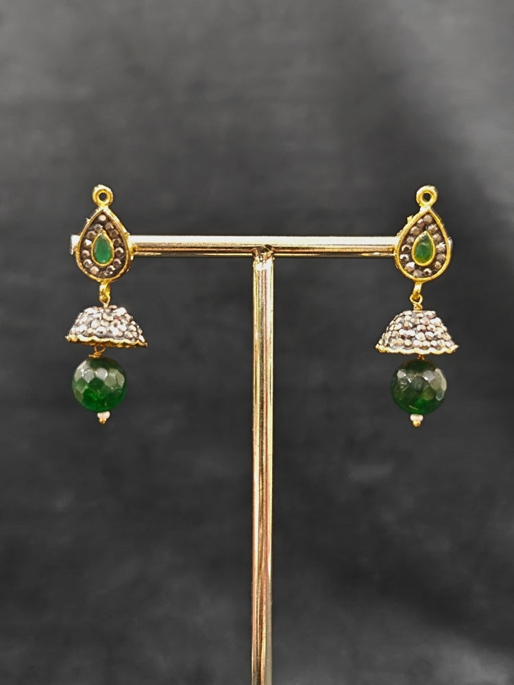 Close-up of an ornate traditional Dark Green Collar jewellery set and earrings with Dark Green Crystals Beads, Pearls, Chatten Squares and Colored Stones. Mehendi ceremony look completed with a handcrafted Pearl jewelry set. Bride showcasing a traditional Pearl artificial jewelry set in India.