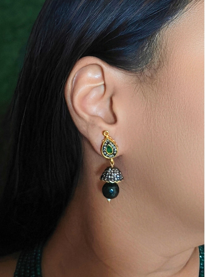 Close-up of a woman wearing an ornate traditional Dark Green Collar jewellery set and earrings with Dark Green Crystals Beads, Pearls, Chatten Squares and Colored Stones. Mehendi ceremony look completed with a handcrafted Pearl jewelry set. Bride showcasing a traditional Pearl artificial jewelry set in India.
