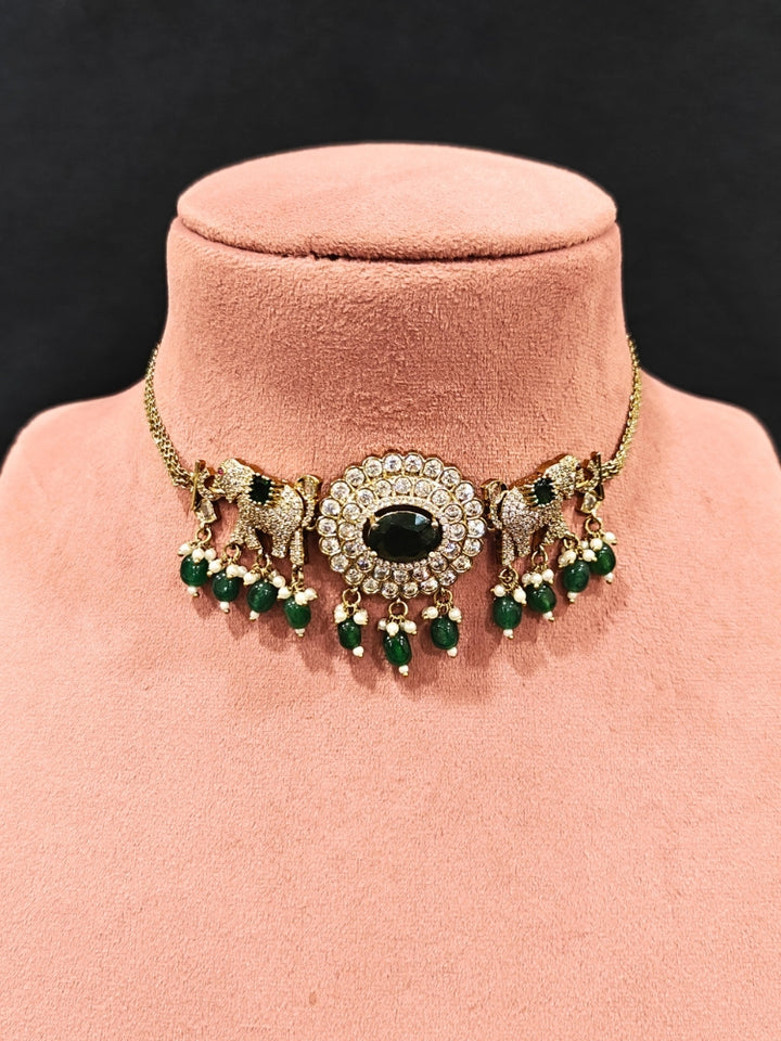 Close-up of an ornate traditional Dark Green (Mehendi gold Polish) Choker Diamond jewellery set and earrings with American Diamond, Colored Stone and Pearls. Elegant festive look with a high-quality imitation American diamond necklace set. A luxury American diamond necklace set styled beautifully for a wedding guest look in India.