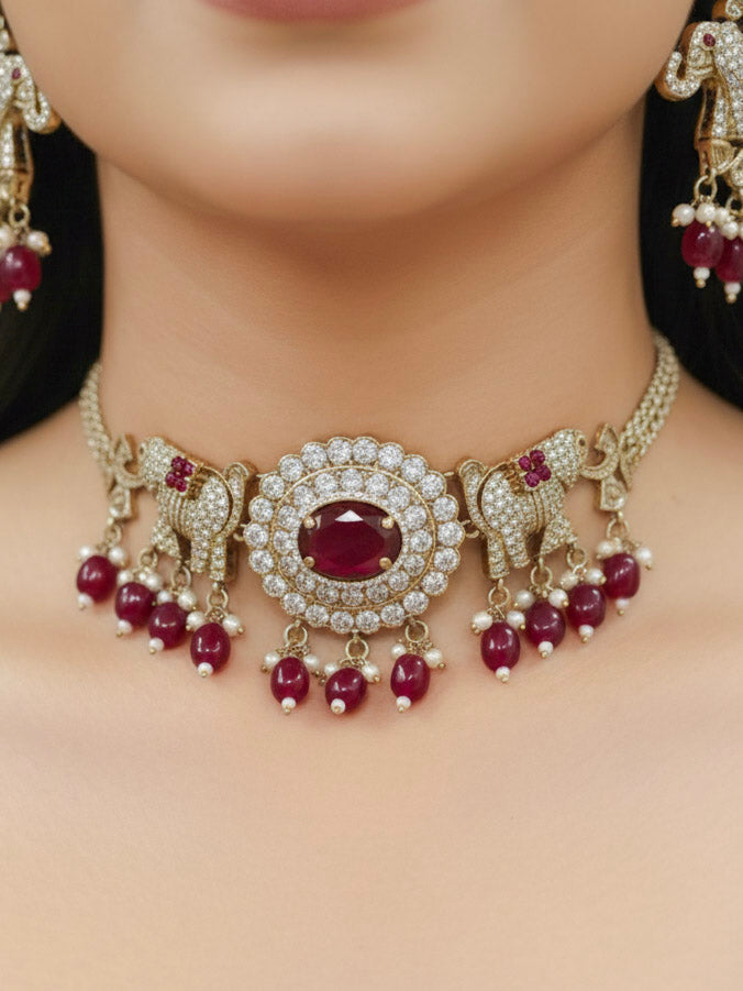 Close-up of a woman wearing an ornate traditional Maroon (Mehendi gold Polish) Choker Diamond jewellery set and earrings with American Diamond, Pearls and Colored Stone. Elegant festive look with a high-quality imitation American diamond necklace set. A woman wearing a luxury American diamond necklace set styled beautifully for a wedding guest look in India.