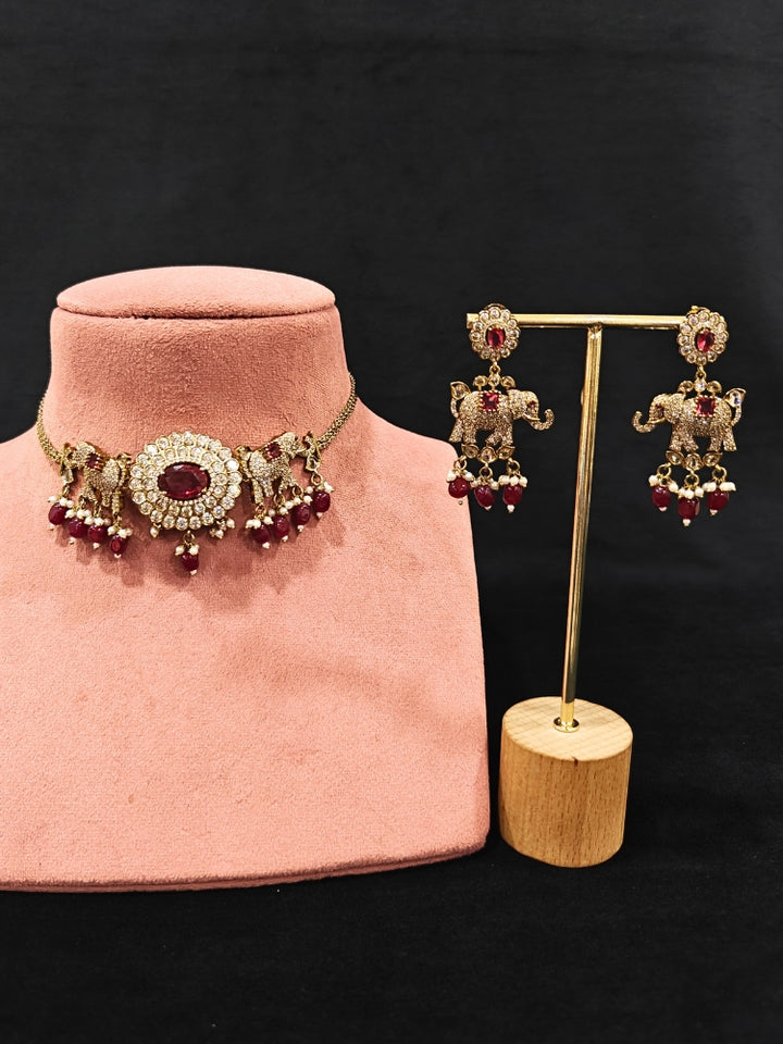 Close-up of an ornate traditional Maroon (Mehendi gold Polish) Choker Diamond jewellery set and earrings with American Diamond, Pearls and Colored Stone. Elegant festive look with a high-quality imitation American diamond necklace set. A luxury American diamond necklace set styled beautifully for a wedding guest look in India.