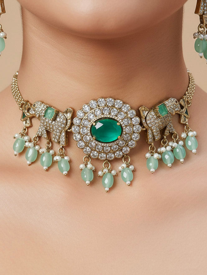 Close-up of a woman wearing an ornate traditional Mint Green (Mehendi gold Polish) Choker Diamond jewellery set and earrings with American Diamond, Pearls and Colored Stone. Elegant festive look with a high-quality imitation American diamond necklace set. A woman wearing a luxury American diamond necklace set styled beautifully for a wedding guest look in India.