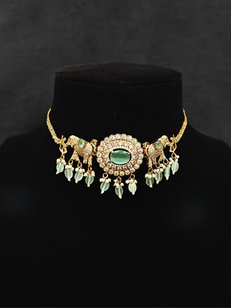 Close-up of an ornate traditional Mint Green (Mehendi gold Polish) Choker Diamond jewellery set and earrings with American Diamond, Pearls and Colored Stone. Elegant festive look with a high-quality imitation American diamond necklace set. A luxury American diamond necklace set styled beautifully for a wedding guest look in India.