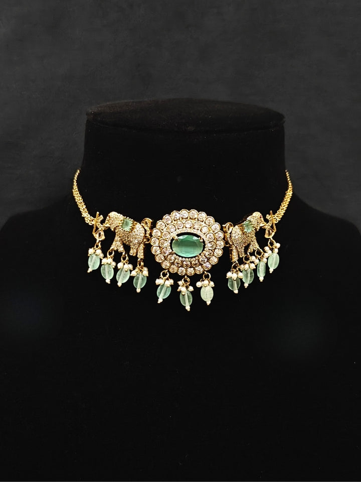 Close-up of an ornate traditional Mint Green (Mehendi gold Polish) Choker Diamond jewellery set and earrings with American Diamond, Pearls and Colored Stone. Elegant festive look with a high-quality imitation American diamond necklace set. A luxury American diamond necklace set styled beautifully for a wedding guest look in India.